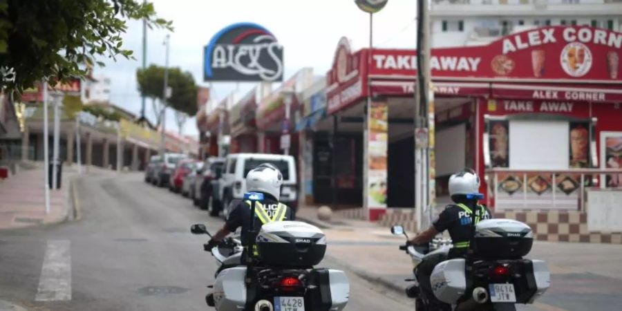 Polizisten überwachen die Lokalsperrungen auf einer Strasse in der Touristenhochburg Magaluf. Foto: Joan Mateu/AP/dpa