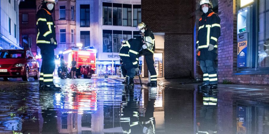 Feuerwehrleute pumpen in Hamburg Wasser von einer überfluteten Strasse ab.
