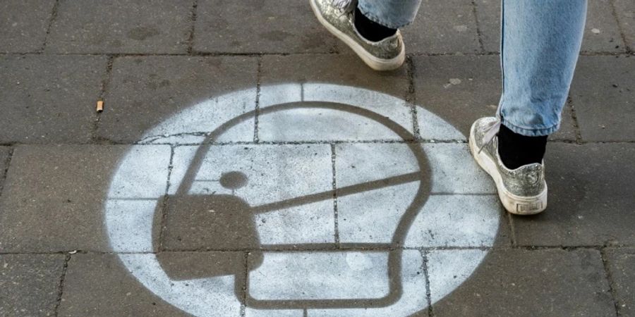 Hinweis zum Maskentragen auf einem Gehweg