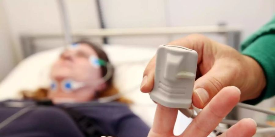 Eine Schlafpatientin wird von einem Krankenpfleger im Schlaflabor der Kliniken Essen-Mitte an Elektroden angeschlossen. Foto: Roland Weihrauch/dpa
