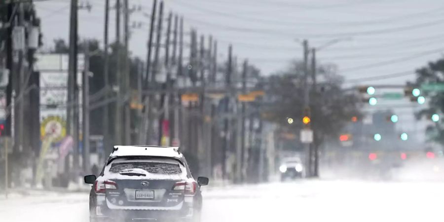 Ein Auto fährt auf einer zugeschneiten Strasse. Im südlichen US-Bundesstaat Texas sind wegen ungewöhnlich kalten Winterwetters Hunderttausende Menschen mindestens zeitweise ohne Strom gewesen. Foto: David J. Phillip/AP/dpa