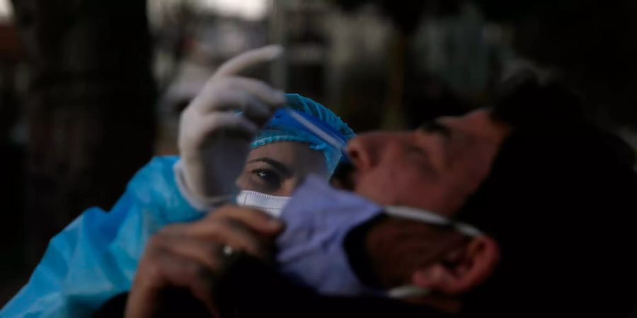 Eine medizinische Mitarbeiterin der Nationalen Gesundheitsorganisation (EODY) führt einen Corona-Schnelltest bei einem Polizisten durch. Griechenland befindet sich im Lockdown. Foto: Thanassis Stavrakis/AP/dpa