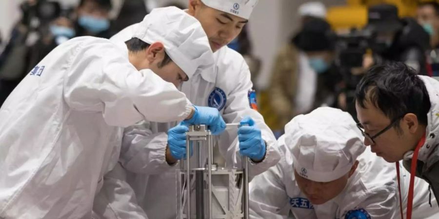 Chinesische Wissenschaftler in Peking beim Wiegen der Gesteinsproben vom Mond. Foto: Jin Liwang/Xinhua/dpa