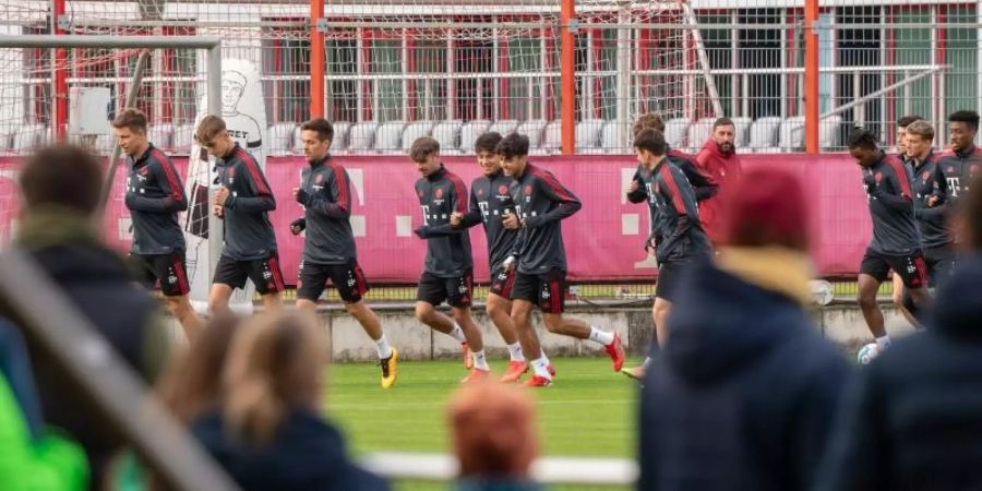 Nach langer Zeit wieder ein öffentliches Training: Spieler und Trainer des FC Bayern München laufen sich vor anwesenden Fans warm. Foto: Peter Kneffel/dpa