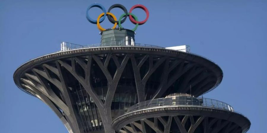 Die olympischen Ringe sind auf der Spitze des Olympiaturms in Peking zu sehen. Foto: Mark Schiefelbein/AP/dpa