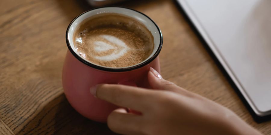 Hand mit Tasse Kaffee Latte