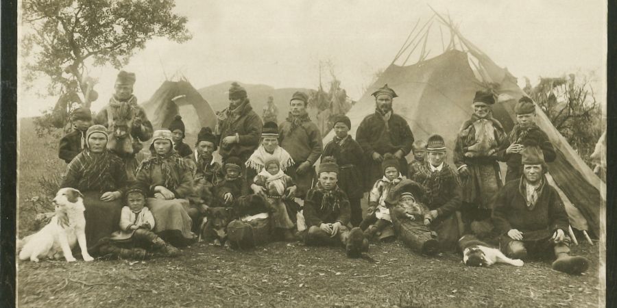 Ein Gruppenporträt einer Samenfamilie vor Zeltkoten bei Tromsø in Nordskandinavien aus dem Jahr 1898.