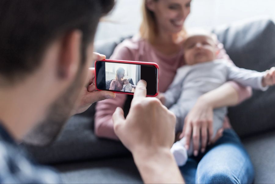 Vater macht Foto von Baby mit Mutter