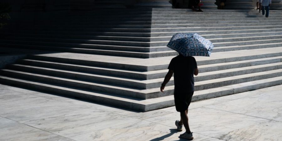 ARCHIV - Ein Besucher steigt während einer Hitzewarnung mit einem Schirm in der Hand die Eingangstreppe des Jefferson Memorials hinauf. Foto: Nathan Howard/AP/dpa