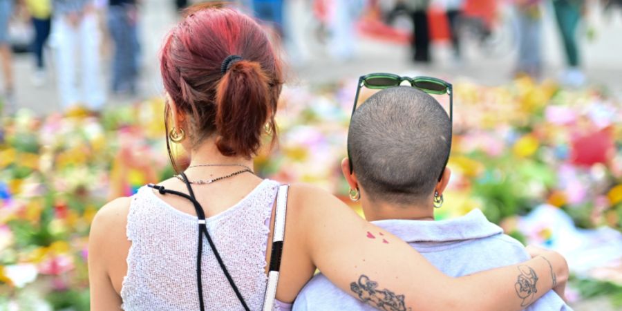 dpatopbilder - Menschen stehen an Beileidsbekundungen Blumen, Flaggen und Kerzen, die vor dem Brandenburger Tor abgelegt wurden. Foto: Sebastian Gollnow/dpa
