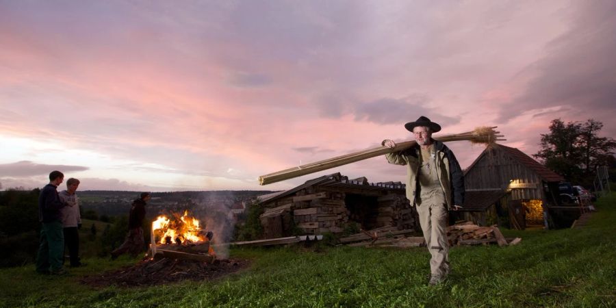 Mann Baumstamm Feuer Dämmerung