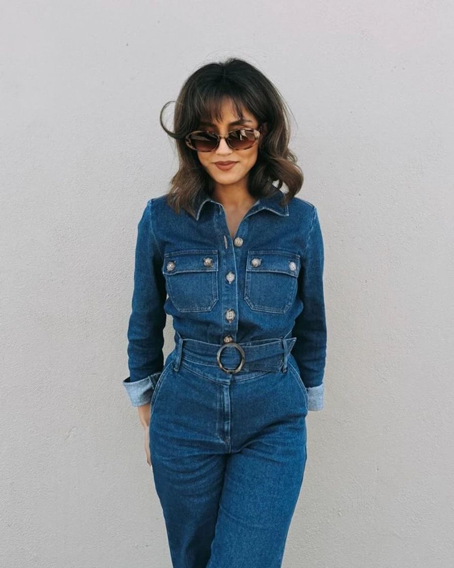 frau, jeans-jumpsuit tragend, weisser hintergrund