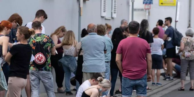 Insgesamt mehr als 1500 Menschen warten bei sommerlichen Temperaturen im Freien auf Einlass in eine Arztpraxis im hessischen Babenhausen. Foto: Boris Roessler/dpa
