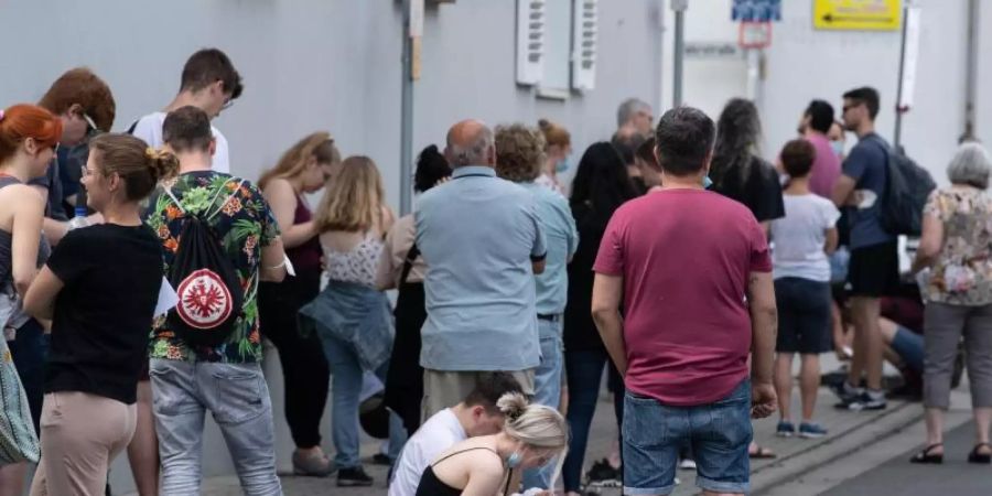Insgesamt mehr als 1500 Menschen warten bei sommerlichen Temperaturen im Freien auf Einlass in eine Arztpraxis im hessischen Babenhausen. Foto: Boris Roessler/dpa