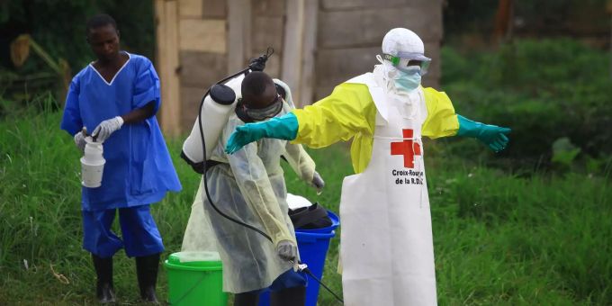 Ein Helfer vom Roten Kreuz wird nach einem Einsatz in einem Ebola-Behandlungszentrum von einem Kollegen mit Desinfektionsmittel eingesprüht. Ebola-Helfer im Kongo