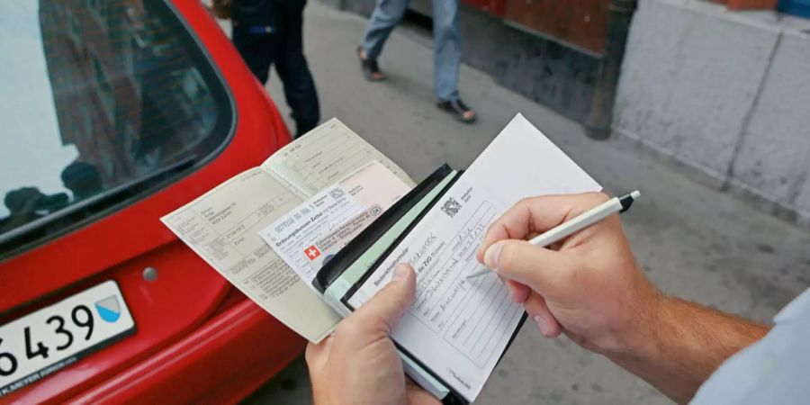 Ein Zürcher Polizist stellt eine Busse aus.
