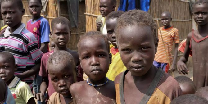 Mehrere Jungen blicken in einem sudanesischen Dorf in die Kamera.