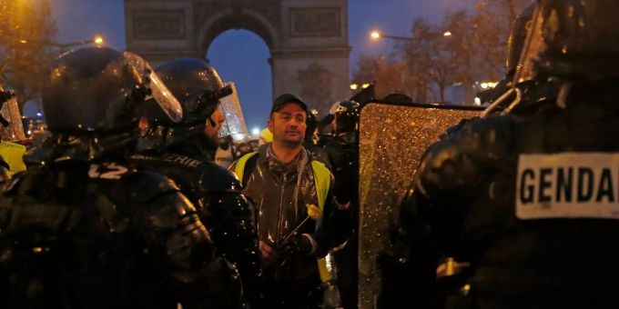 Ein «Geldwesten»-Demonstrant hält eine Blume in seinen Händen und steht vor Bereitschaftspolizisten. Ein «Geldwesten»-Demonstrant hält eine Blume in seinen Händen und steht vor Bereitschaftspolizisten.