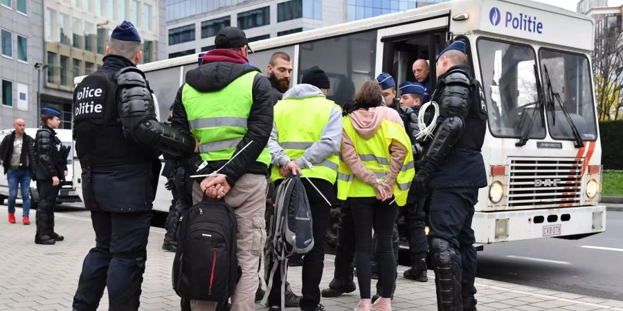 Polizisten verhaften Demonstranten in gelben Warnweste.