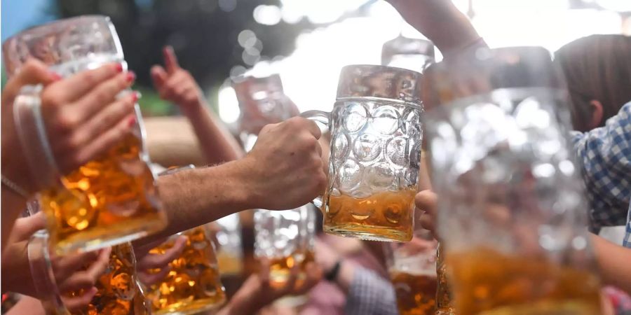 Wiesn-Besucher prosten sich gegenseitig mit Bierkrügen zu.