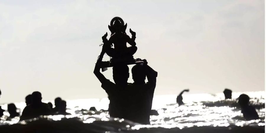 Hinduistische Gläubige tragen eine Statue des Gottes Ganesha ins Meer, um im Rahmen der zehntägigen Feierlichkeiten zum Ganesha-Festival das Gottesbild ins Wasser zu werfen.