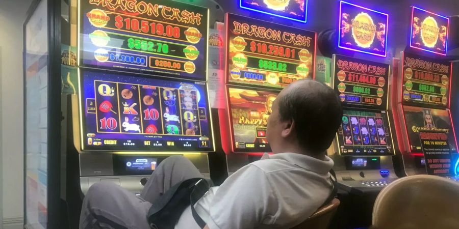 In einer Kneipe der australischen Millionen-Metropole sitzt ein Mann vor einer der elektronischen Pokermaschinen, den sogenannten Pokies.