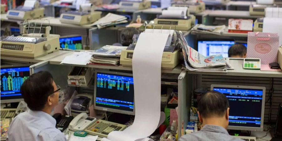 Börsenmakler arbeiten in Hongkong in ihren Arbeitsplätzen.