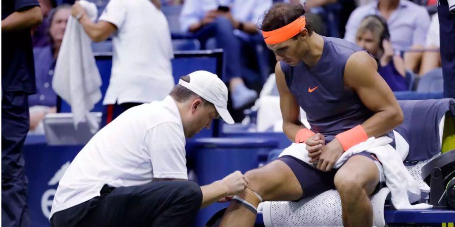 Rafael Nadal wird von einem Trainer behandelt.