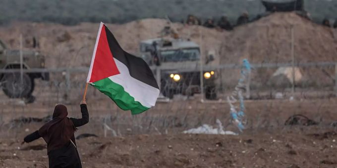 Eine Frau schwenkt die palästinensische Fahne vor dem israelischen Militär an der Grenze zwischen dem Gazastreifen und Israel. gaza