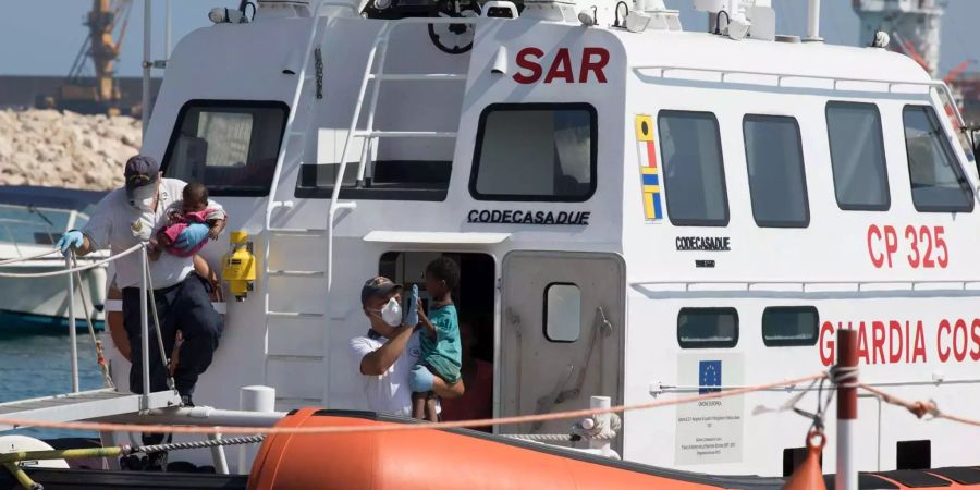 Sanitäter tragen Kinder von Bord eines Schiffes der italienischen Küstenwache.