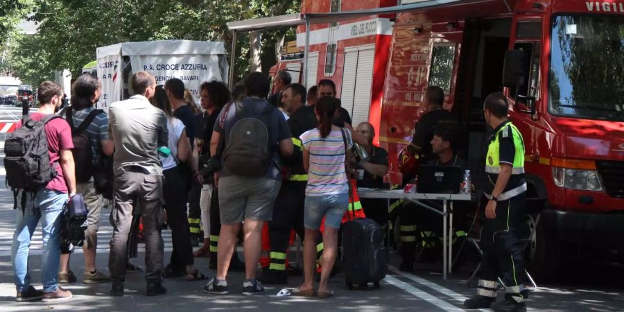 Einige Bewohner der elf nach dem Brückeneinsturz evakuierten Häuser stehen an einem Fahrzeug der Feuerwehr.