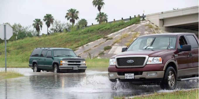 Zwei Autos im Ford fahren durch ein überschwemmtes Gebiet. Zwei Autos im Ford fahren durch ein überschwemmtes Gebiet.