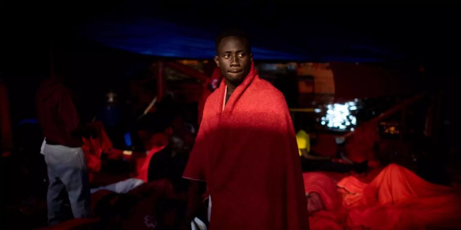 Spanien, Algeciras: Ein Flüchtling steht nach seiner Rettung durch den spanischen Seerettungsdienst aus der Strasse von Gibraltar in eine rote Decke gehüllt im Hafen.