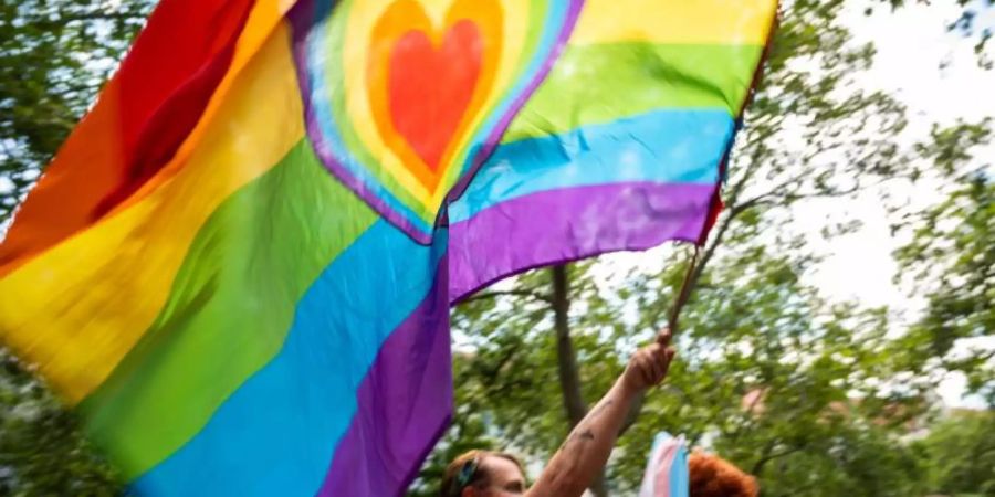 Ein Teilnehmer der «CSD Berlin Pride» trägt eine Regenbogenfarbene Flagge mit einem Herz. (Symbolbild). Foto: Christophe Gateau/dpa