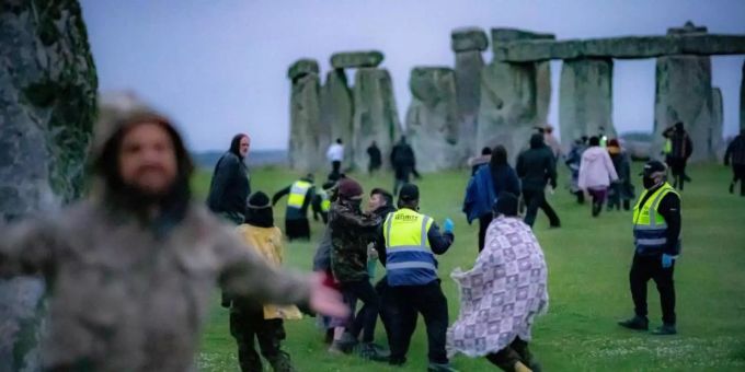Menschen springen über einen Zaun und bahnen sich ihren Weg an Sicherheitspersonal vorbei in Richtung Stonehenge. Foto: Ben Birchall/PA Wire/dpa Menschen springen über einen Zaun und bahnen sich ihren Weg an Sicherheitspersonal vorbei in Richtung Stonehenge. Foto: Ben Birchall/PA Wire/dpa