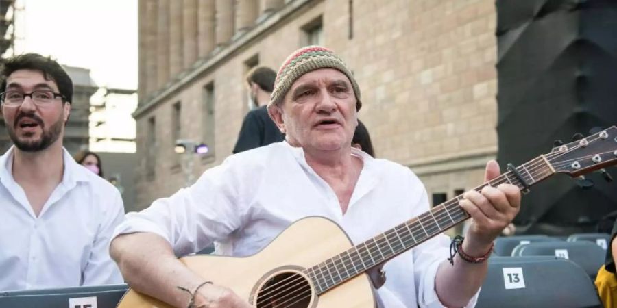 Protagonist Dieter Bachmann (M) spielt Gitarre auf der Museumsinsel vor der Vorführung des Films «Herr Bachmann und seine Klasse» beim Open Air Cinema im Rahmen der Berlinale. Foto: Stefanie Loos/AFP-POOL/dpa