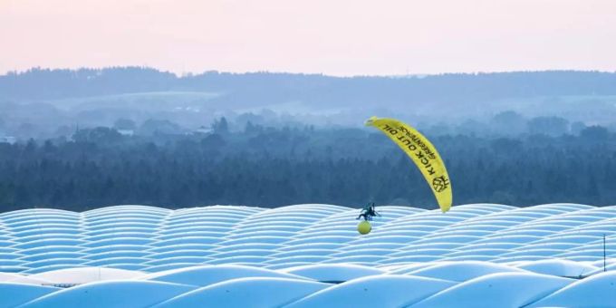 Ein Aktivist von Greenpeace landet mit einem Gleitschirm im Stadion. greenpeace