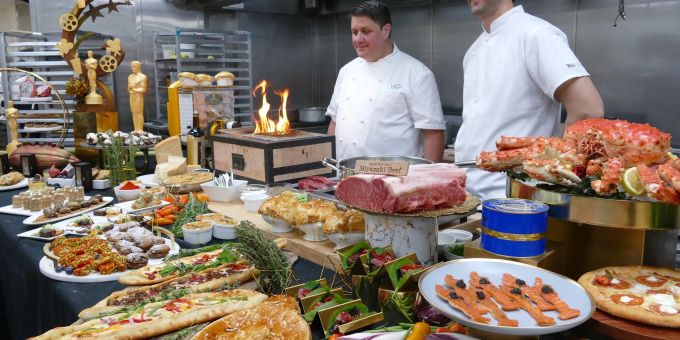 Zwei Köche stehen hinter einem Buffet. Zwei Köche stehen hinter einem Buffet.