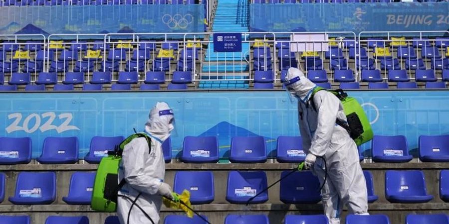 Arbeiter in Schutzkleidung desinfizieren Sitze nach dem Big-Air-Finale. Foto: Jae C. Hong/AP/dpa