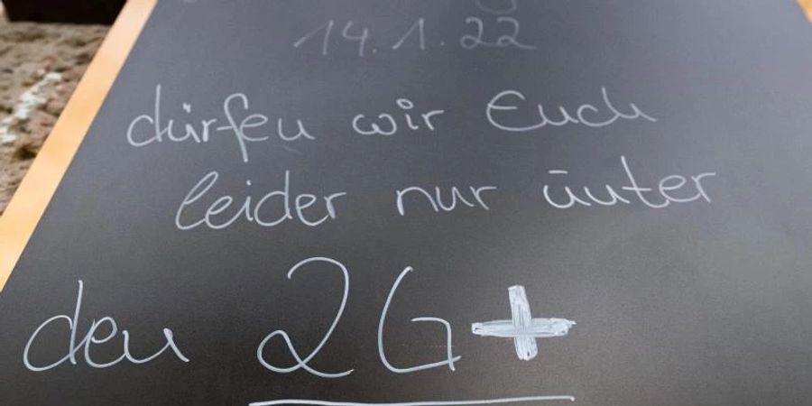 Auf einem Schild wird vor einem Cafe auf die 2G-plus-Regel hingewiesen. Wer genesen ist, behält diesen Status künftig nur noch drei statt sechs Monate. Foto: Robert Michael/dpa-Zentralbild/dpa