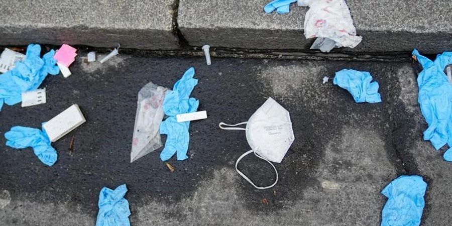 Einmalhandschuhe, FFP2-Maske und benutzte Corona-Antigen-Testkits liegen auf der Strasse vor einem Corona-Testzentrum. Foto: Kay Nietfeld/dpa