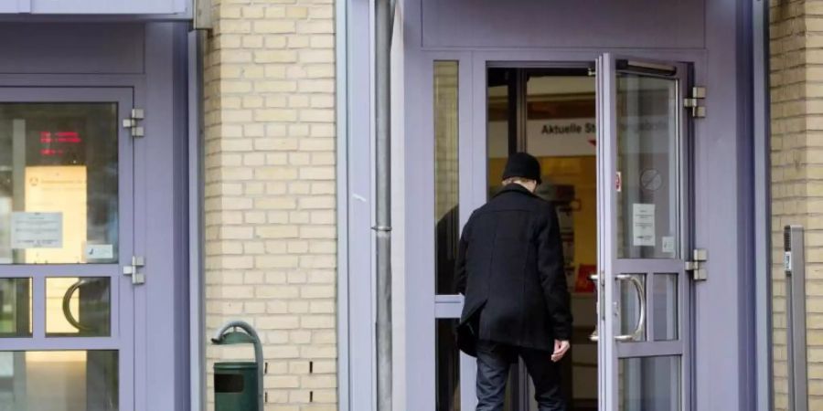Ein Mann geht in ein Gebäude der Arbeitsagentur in Flensburg. Foto: Christian Charisius