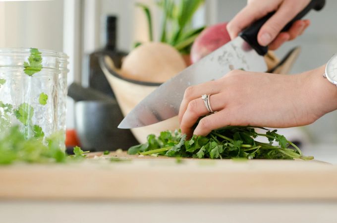 Koriander ist ein echtes Superkraut: reich an Antioxidantien wie Chlorophyll und Vitamin C. Zusätzlich liefert das Gewürz Vitamin A und Folsäure. Koriander Küche Messer hacken Schneidebrett