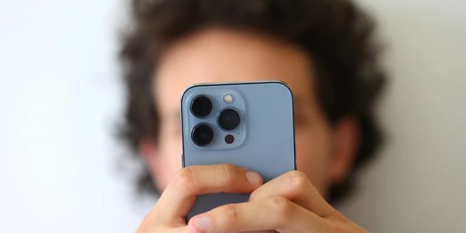 Ein junger Mann schaut auf sein Smartphone. Smartphone