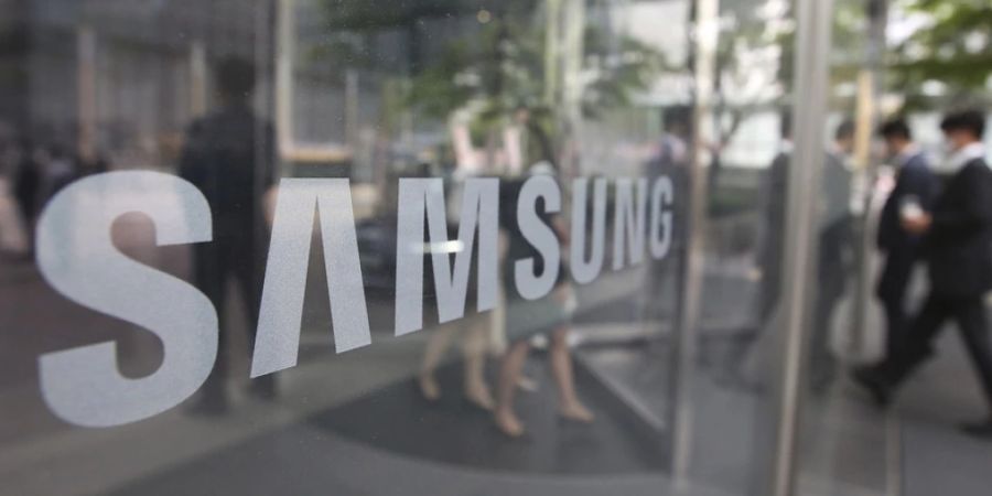 Employees walk past a logo of the Samsung Electronics Co. at its office in Seoul, South Korea, Wednesday, April 28, 2021. Samsung's founding family will donate tens of thousands of rare artworks, including Picassos and Dalis, and give hundreds of millions of dollars to medical research to help them pay a massive inheritance tax following last year's death of chairman Lee Kun-Hee. (AP Photo/Ahn Young-joon)