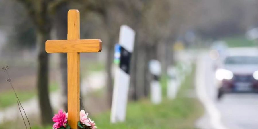 Ein Kreuz zum Gedenken an ein Opfer eines Verkehrsunfalls steht an einer Landstrasse. Foto: Julian Stratenschulte/dpa