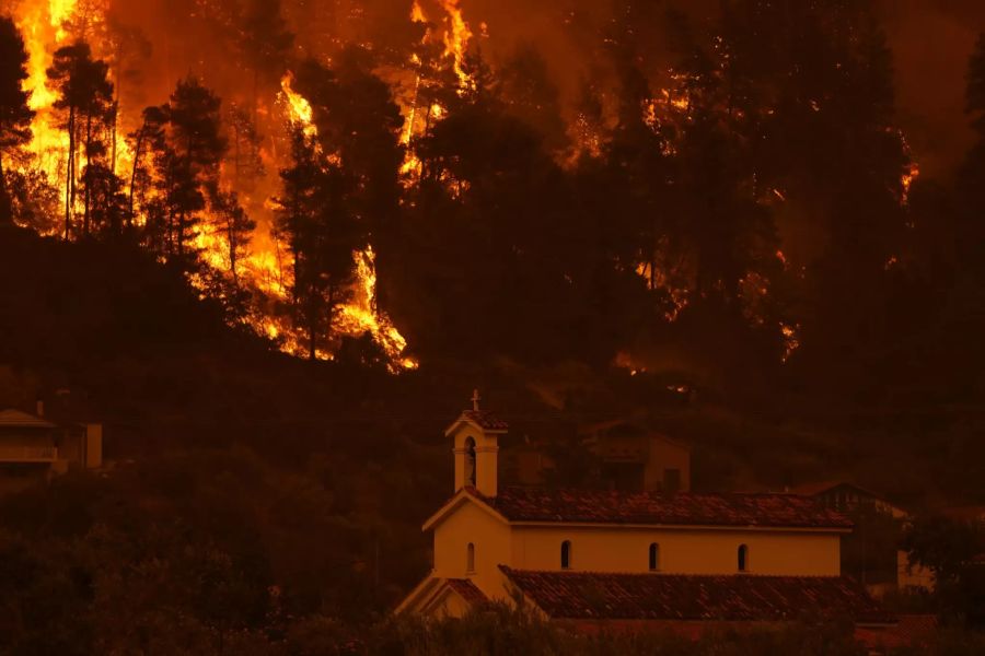 Flammen nähern sich einer Kriche im Dorf Gouves.