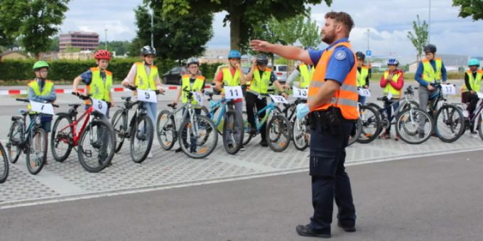 Die Schülerinnen und Schüler bekommen letzte Instruktionen vom Polizisten für den Geschicklichkeitsparcours. Veloprüfung Schülerinnen Schüler Polizei