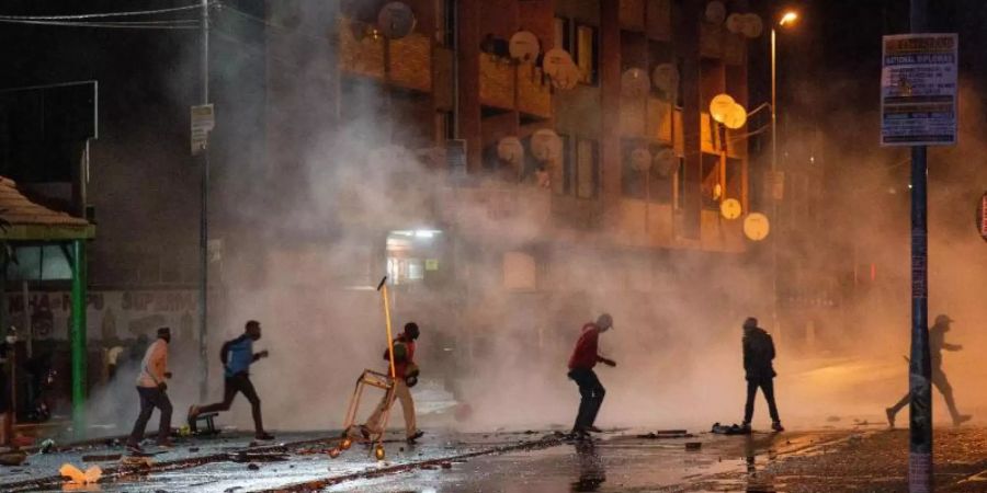 Demonstranten in Johannesburg laufen weg nachdem die Polizei Tränengaskanistern eingesetzt hat. Foto: Yeshiel/XinHua/dpa