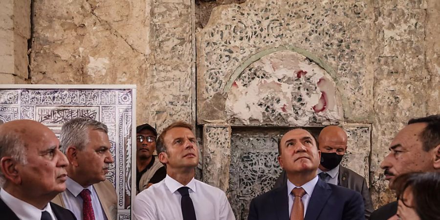 Emmanuel Macron (M), Präsident von Frankreich, besucht die Al-Nuri-Moschee in Mossul. Dabei sagt er der dortigen christlichen Minderheit Frankreichs Unterstützung zu. Foto: Ismael Adnan/dpa